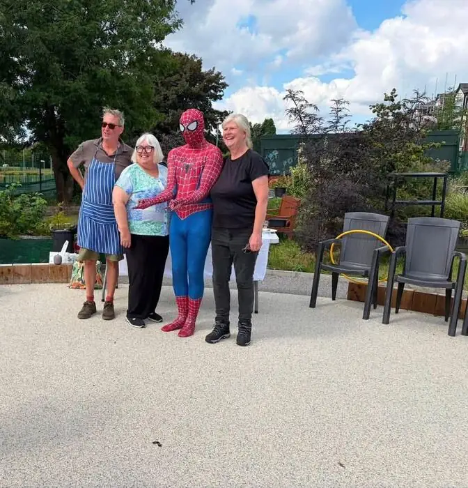 Spider-Man posing with a small group at a community charity event