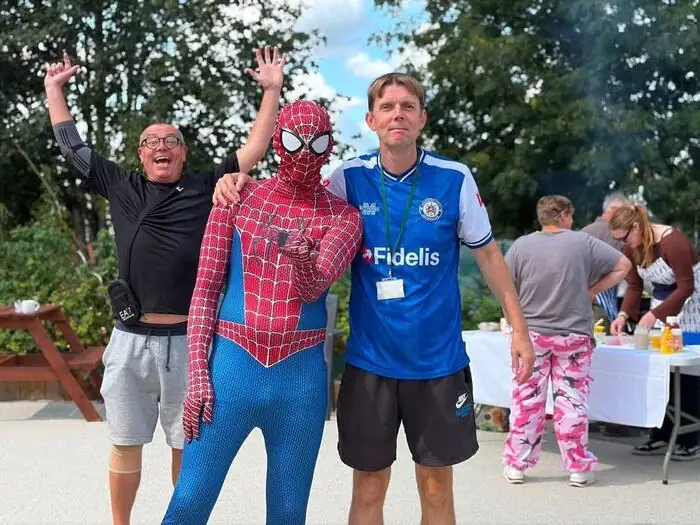 Spider-Man posing with two guests at a charity event
