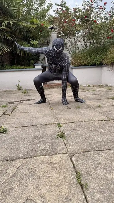 Spider-Man in a black symbiote-style suit crouching in a garden
