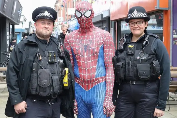 Spider-Man posing with two community police officers on the high street