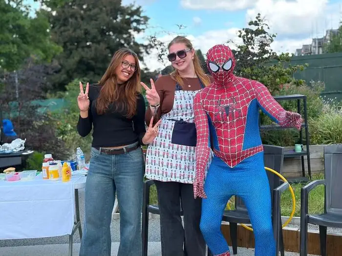 Spider-Man posing with two volunteers at a charity BBQ